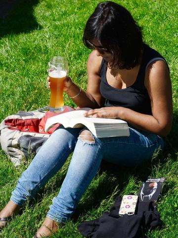 woman reading outside with a beer